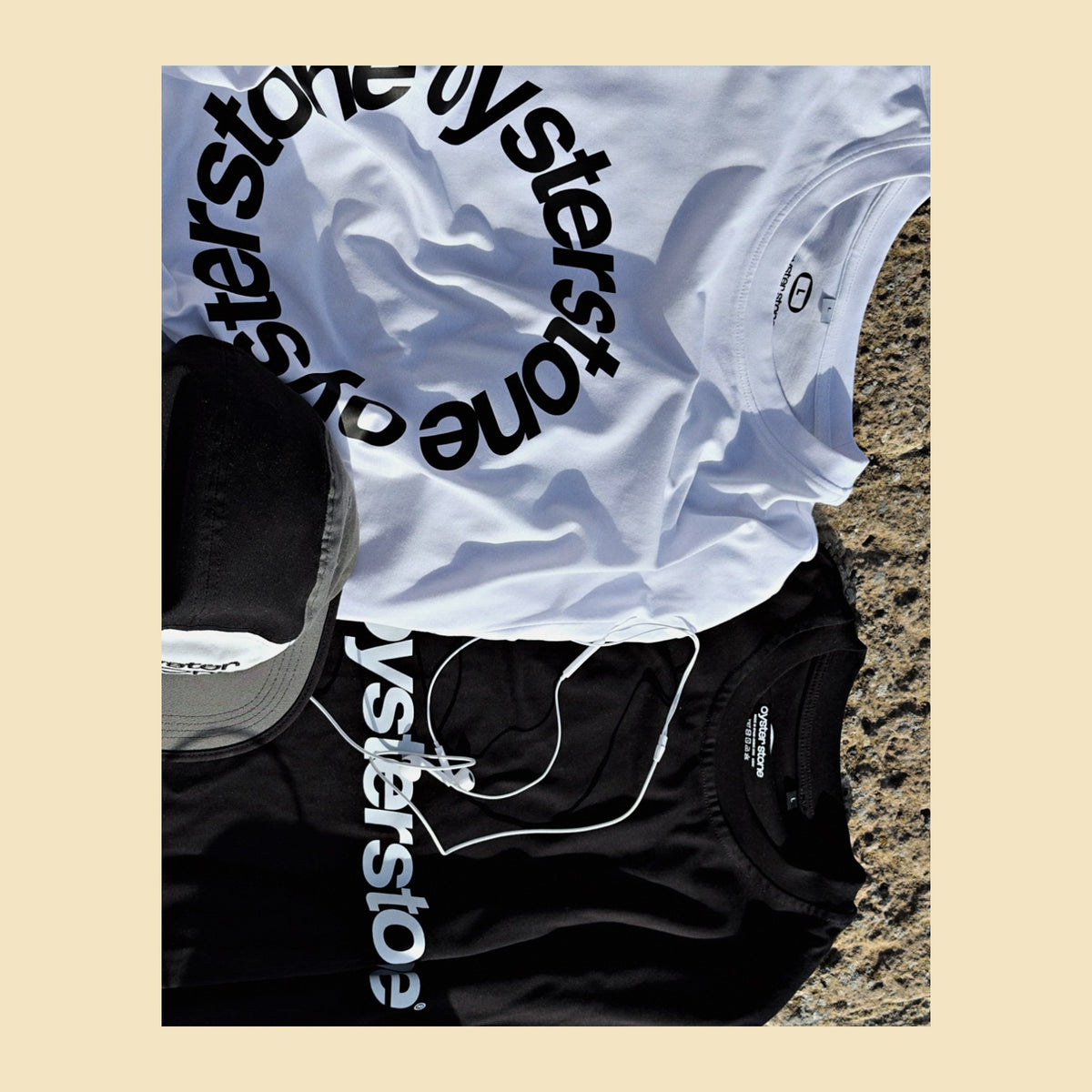 Basic Tee MEMORIES blanca doblada junto a la gorra de Oyster Stone