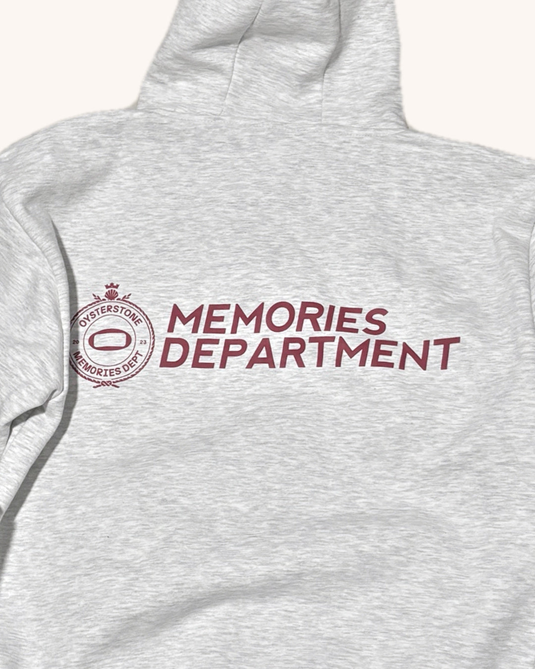 Espalda de la Hoodie MEMORIES gris con el escudo y el texto Memories Department en granate