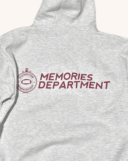 Espalda de la Hoodie MEMORIES gris con el escudo y el texto Memories Department en granate
