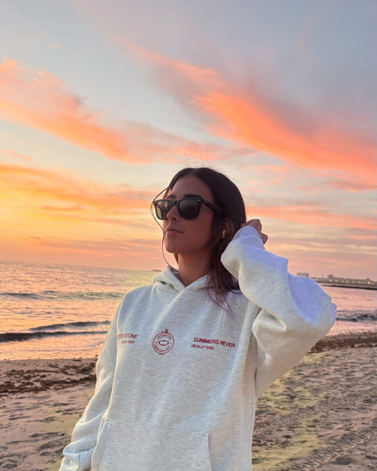 Hoodie MEMORIES gris puesta, vista delantera en la playa de Cádiz al atardecer