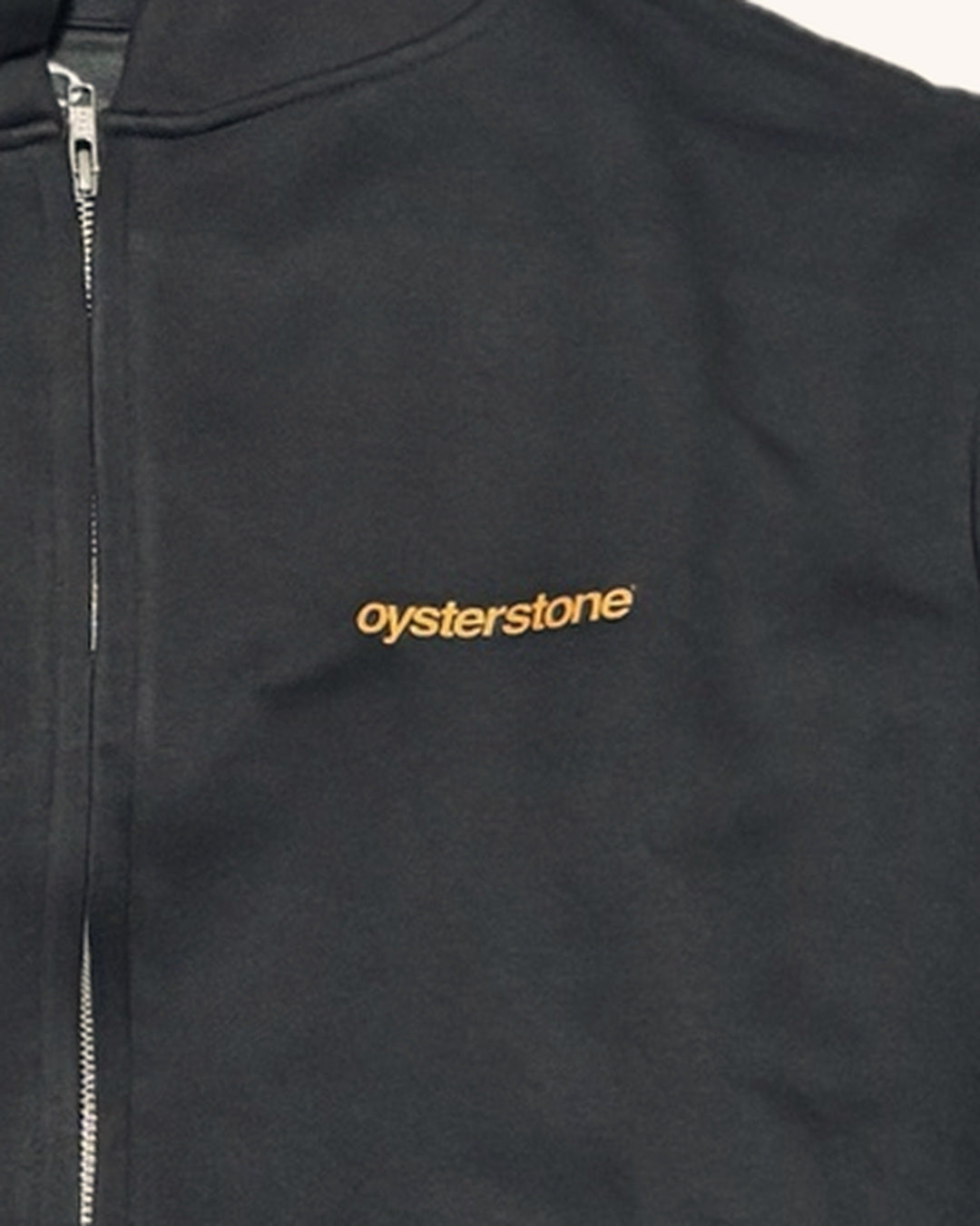 Detalle del logo oysterstone naranja en el pecho de la Zip Hoodie MEMORIES negro lavado