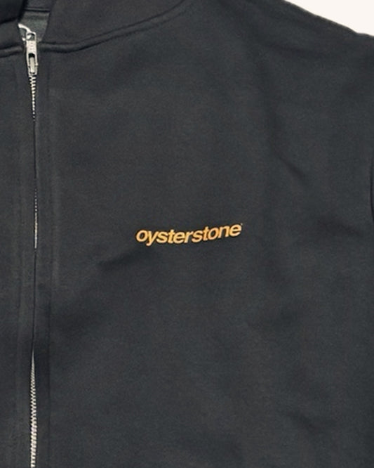 Detalle del logo oysterstone naranja en el pecho de la Zip Hoodie MEMORIES negro lavado